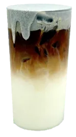 Tall glass of layered iced coffee: white milk at the bottom, dark coffee in the middle, and pale foam on top.